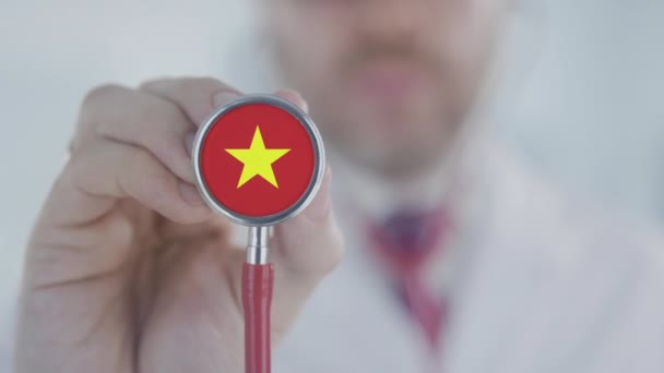 Доктор держит стетоскоп с вьетнамским флагом. Здравоохранение во Вьетнаме — стоковое видео