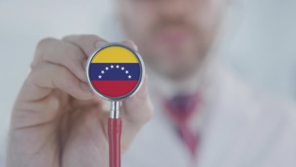 El doctor sostiene la campana del estetoscopio con la bandera venezolana. Salud en Venezuela — Vídeos de Stock