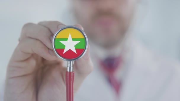 El médico sostiene la campana del estetoscopio con la bandera de Myanmar. Salud en Myanmar — Vídeos de Stock