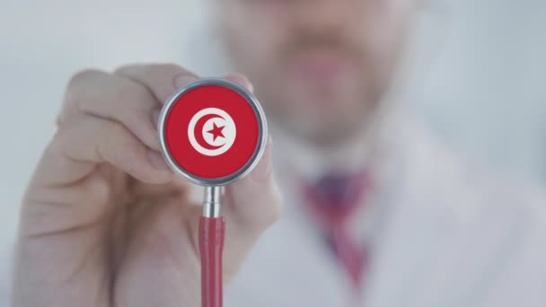 Docteur tient une cloche stéthoscopique avec le drapeau tunisien. Soins de santé en Tunisie — Video