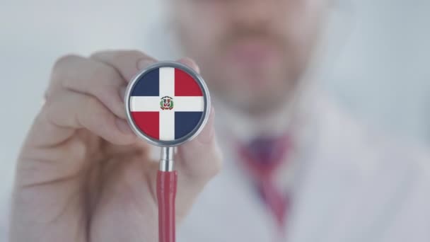 Доктор использует стетоскоп с доминиканским флагом. Здравоохранение в Доминиканской Республике — стоковое видео