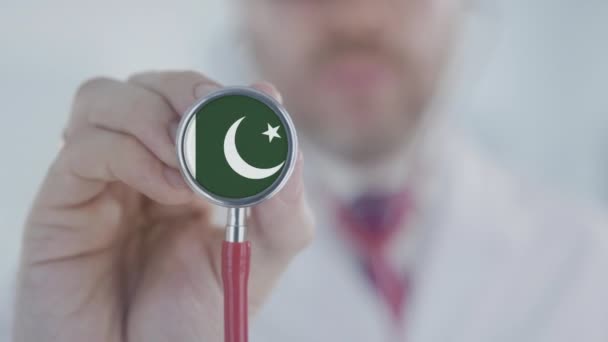 의사가 청진기로 파키스탄 국기를 들고 듣고 있어요. 파키스탄 의료 서비스 — 비디오