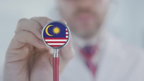 Doctor escuchando con el estetoscopio con la bandera de Malasia. Asistencia sanitaria de Malasia — Vídeo de stock