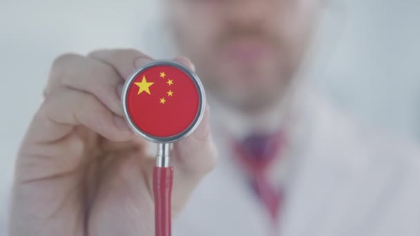 El médico sostiene la campana del estetoscopio con la bandera china. Salud en China — Vídeo de stock