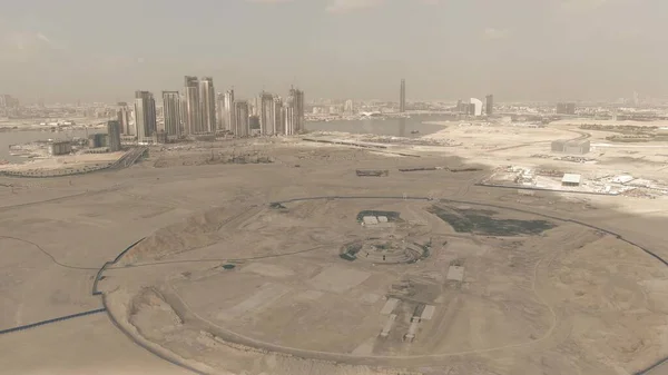 Fotografia aérea de um local de construção do deserto com arranha-céus Dubais como fundo, Emirados Árabes Unidos — Fotografia de Stock