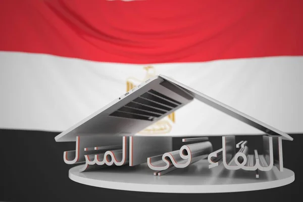 エジプトの旗に対して開かれたノートパソコンの下でアラビア語のホームテキストを保持します。エジプトでのコロナウイルスの自己分離3Dレンダリング — ストック写真