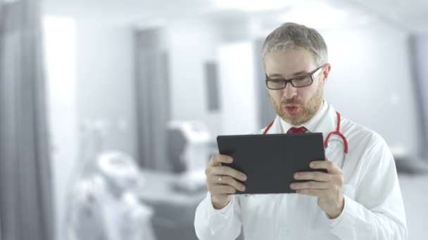 Mannelijke arts gebruikt tablet PC voor telegeneeskunde oproep naar een patiënt. Neergeschoten op rode camera — Stockvideo