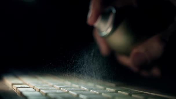 Mit Alkohol Desinfektionsspray, um die Computer-Tastatur zu desinfizieren, Zeitlupe Schuss. Arbeitshygiene während des COVID-19-Ausbruchs — Stockvideo