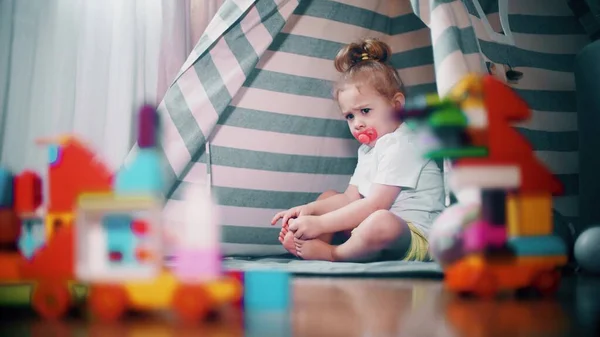 Menina descontente franzido senta-se na tenda de brinquedo teepee em casa. Conceito de autoisolamento — Fotografia de Stock