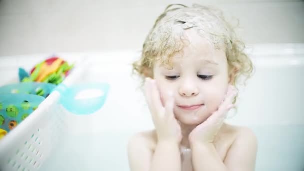 Sevimli sarışın bebek yüzünü ve saçlarını banyoda yıkıyor. — Stok video
