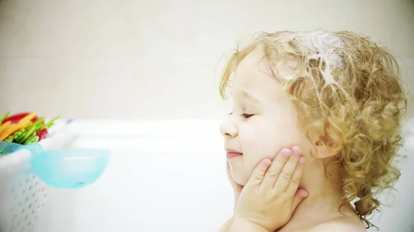 Liebenswertes blondes Mädchen wäscht ihr Gesicht und ihre Haare im Badezimmer — Stockfoto