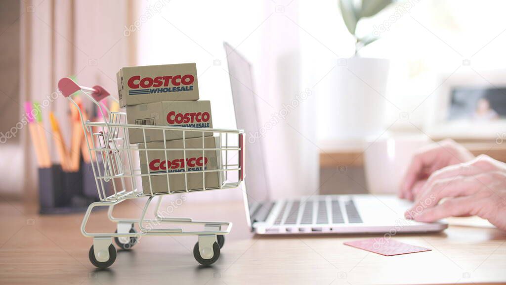 Cartons with logo in shopping trolley near laptop. Editorial online store order related 3D