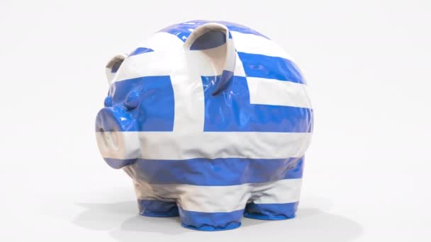 印刷されたギリシャの旗とインフレータブル貯金箱を減少させます。ギリシャ金融危機関連の概念3Dアニメーション — ストック動画