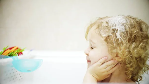 Lockiges blondes Baby wäscht Gesicht und Haare im Badezimmer — Stockfoto
