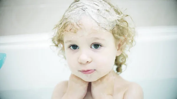 Liebenswertes blondes Mädchen wäscht ihr Gesicht und ihre Haare in der Badewanne — Stockfoto