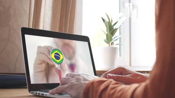 Lekarze doradzają w sprawie aplikacji komputerowej, stetoskopu z brazylijską flagą. Technologia telemedyczna w Brazylii — Zdjęcie stockowe