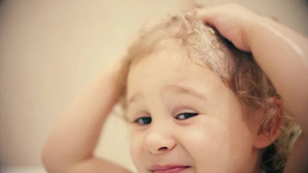 Kleines blondes Mädchen wäscht sich die Haare mit Seife — Stockfoto