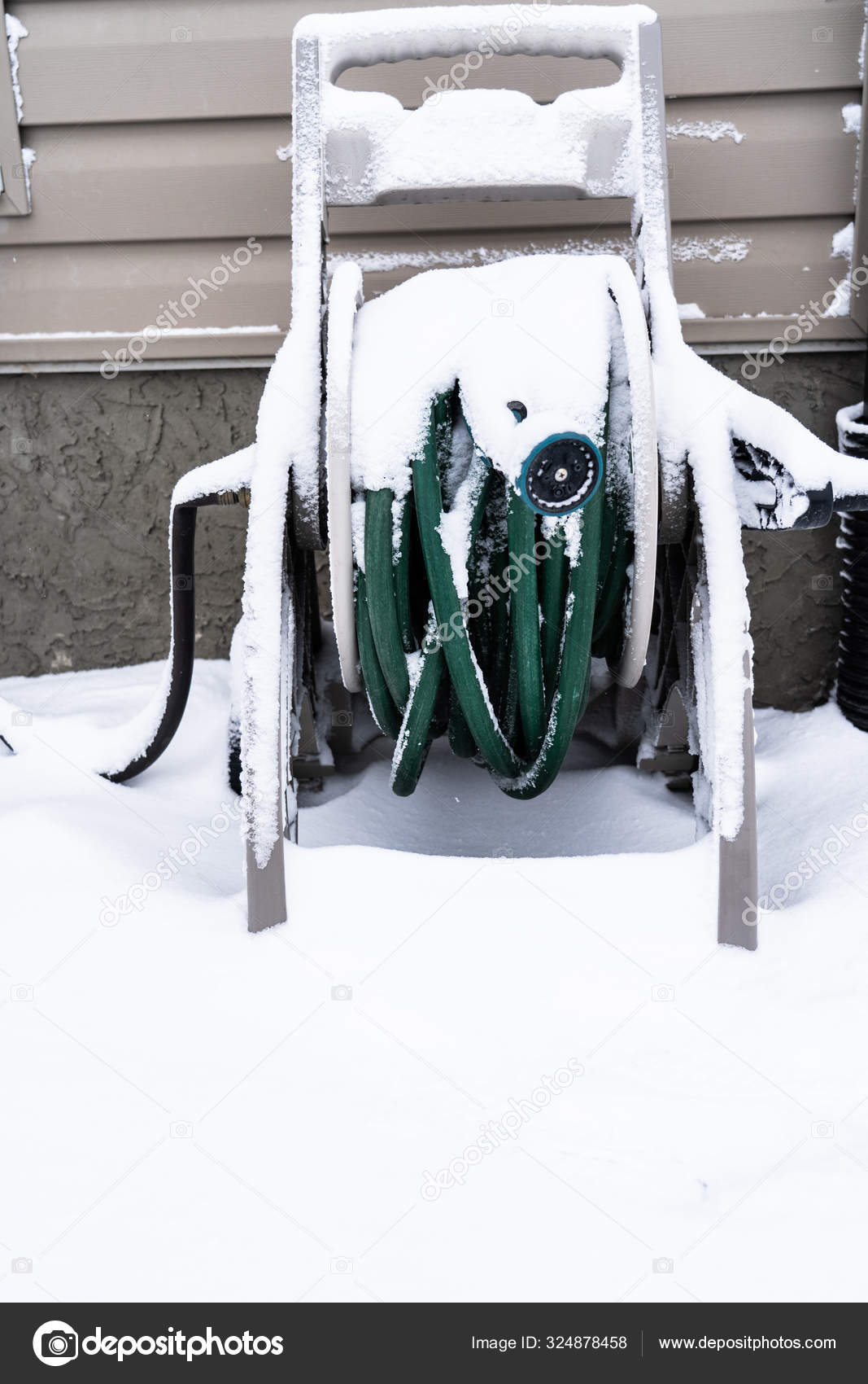 Snow covered garden hose ouside a house in winter — Stock Photo