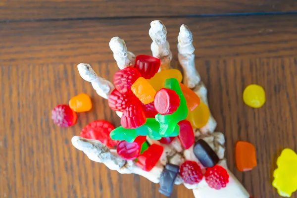 Skeleton hand offering bowl of Candy during halloween — Stock Photo, Image