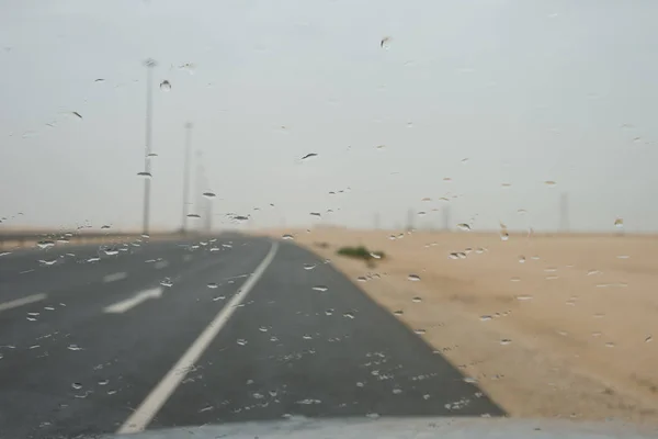 Ökenmotorvägen i Qatar med regndroppar på bilfönstret — Stockfoto