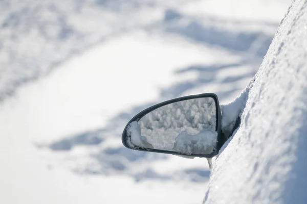 Car rearview side mirror on snow covered car