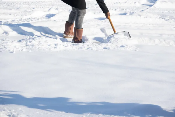 Woman shovelling snow to clear her driveway after winter storm Royalty Free Stock Images