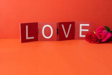 Kırmızı arka planda aşk işareti olan taze kesilmiş güller.