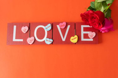 Kırmızı arka planda aşk işareti olan taze kesilmiş güller.