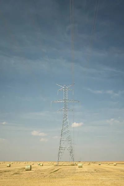 Fardos de heno alrededor de la electricidad Pilón de energía en la carretera rural . —  Fotos de Stock