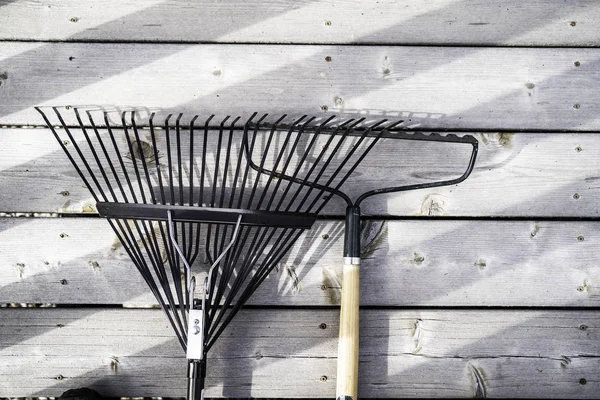 Garden Rakes on wood decking in a residential home — Stock Photo, Image