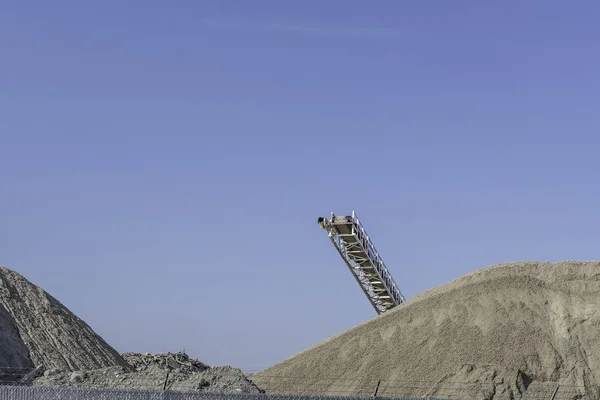 Conveyor crusher on contruction site with Piles of Sand and earth
