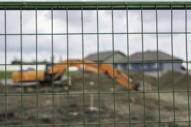 İnşaat alanındaki bir çitin arkasındaki mekanizma ekipmanı.