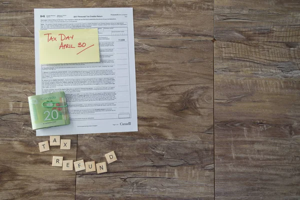 Steuerrückerstattung buchstabiert mit Buchstabenkacheln mit kanadischem Steuerformular und kanadischen Dollars — Stockfoto