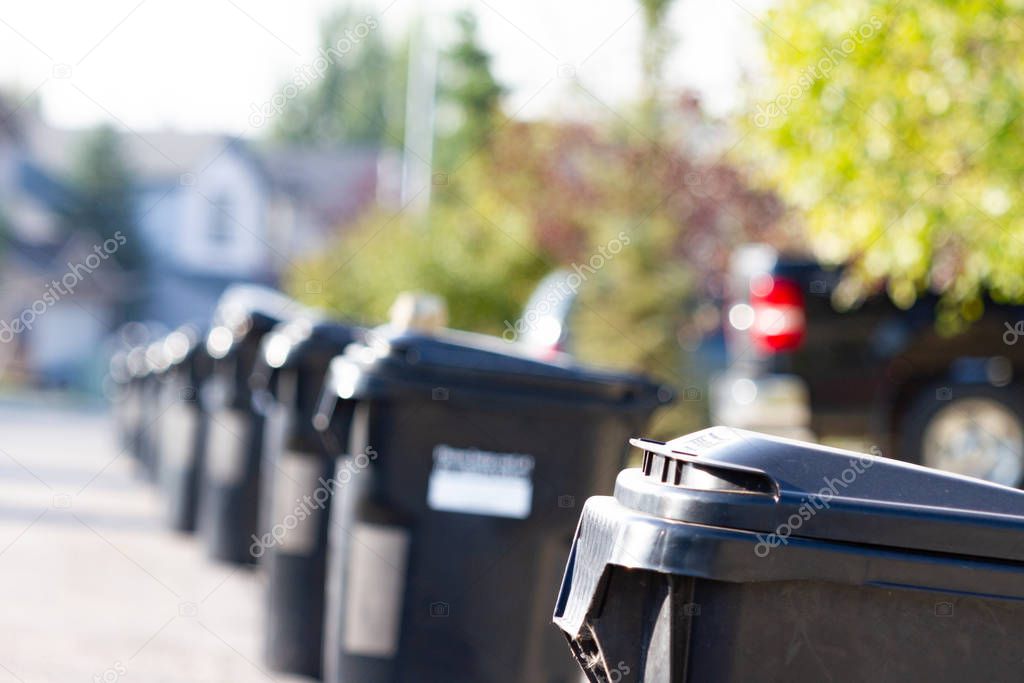 Black plastic Trash bins on a residential street waiting for collection