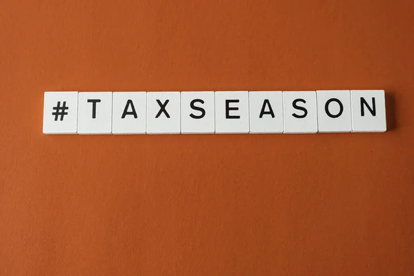 Letter tiles spelling tax season on red backgound