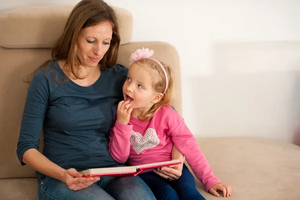 Moeder lezen van een boek van verhaal naar haar cildren op een bank in het leven — Stockfoto