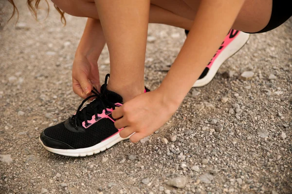 Woman runner tie shoes on a mountain road — Stock Photo, Image