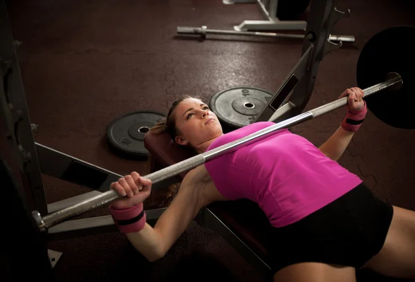 Spor salonunda ağırlık kaldırma egzersizi yapan bir kadın. — Stok fotoğraf