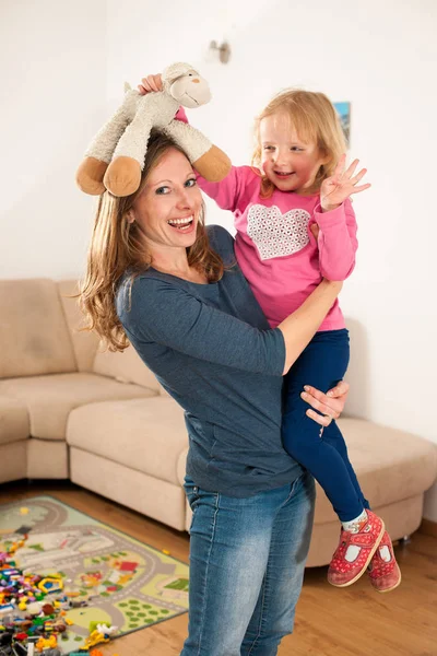 Moeder speelt met haar dochter in woonkamer — Stockfoto