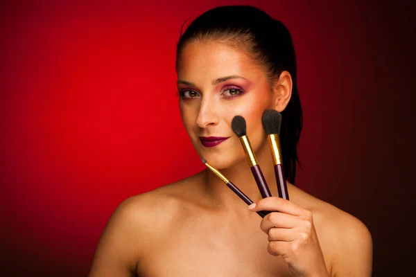 Bela jovem mulher detém pincéis de maquiagem — Fotografia de Stock