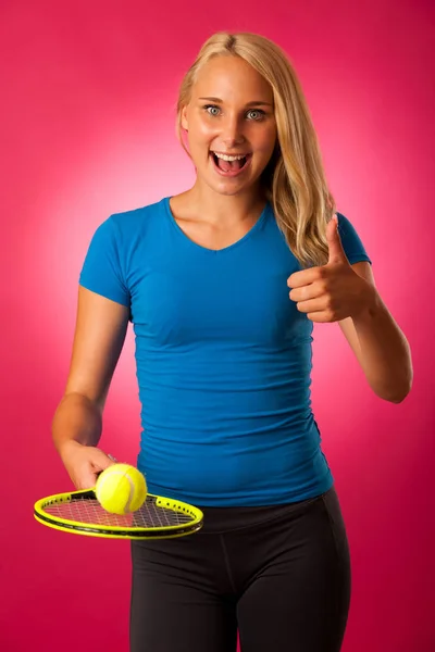 Ajuste jovem mulher com raquete de tênis e bola sobre fundo rosa — Fotografia de Stock