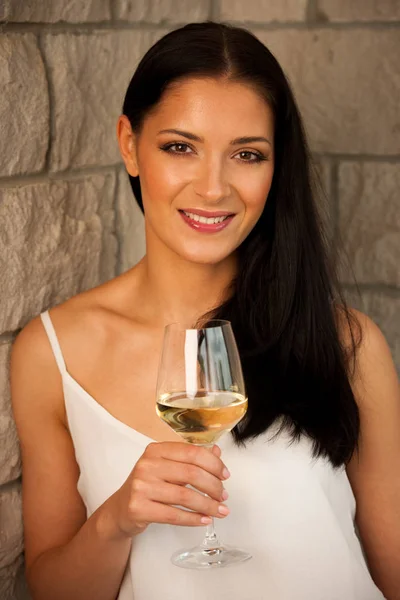 年轻的黑发女人，用一杯白葡萄酒 — 图库照片