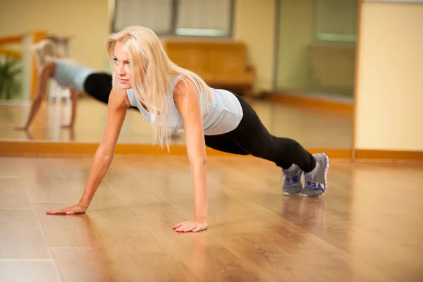 Fit woman works out in gym making push ups — Stock Photo, Image