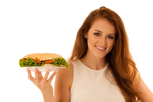 Unhealthy meal - happy young woman eats hamburger isolated over — Stock Photo, Image