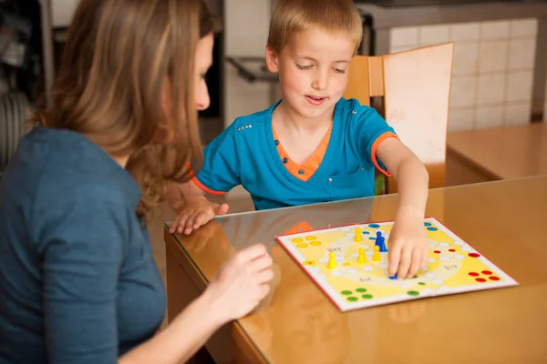어린 소년 거실 테이블에 그의 어머니와 함께 루도 게임을 재생 — 스톡 사진