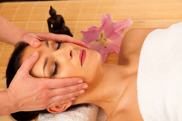 Vacker ung kvinna med ett ansikte som massage i wellness studio - — Stockfoto