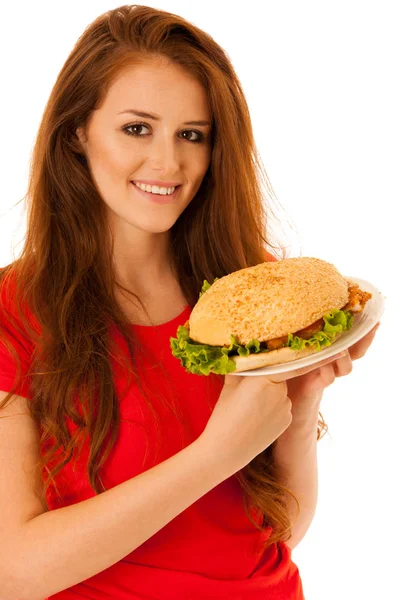 Unhealthy meal - happy young woman eats hamburger isolated over Stock Image