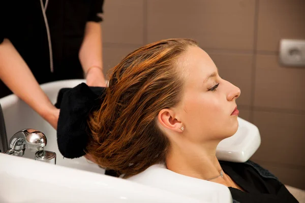 Cabeleireiro no trabalho - cabeleireiro lavando o cabelo ao cliente — Fotografia de Stock