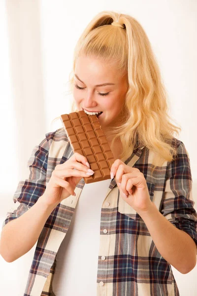 Hermosa mujer rubia se come un gran chocolate — Foto de Stock