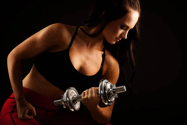 Mooie jonge vrouw werkt met halters in fitness gym — Stockfoto